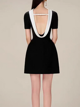 Black dress with white trim on a plain background