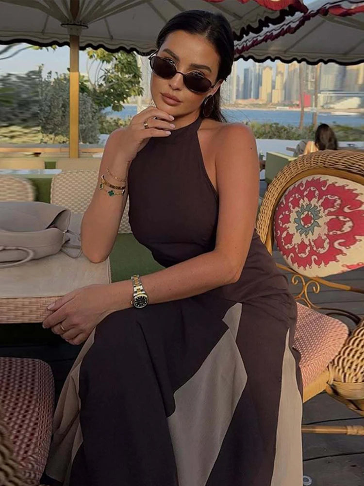 Woman in a brown outfit sitting outdoors with a scenic background