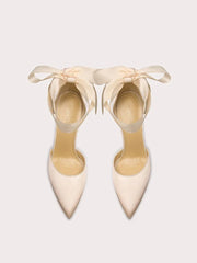 Pair of cream high-heeled shoes with ribbons on a light gray background