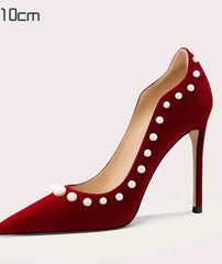 Red high-heeled shoe with pearl embellishments on a light gray background