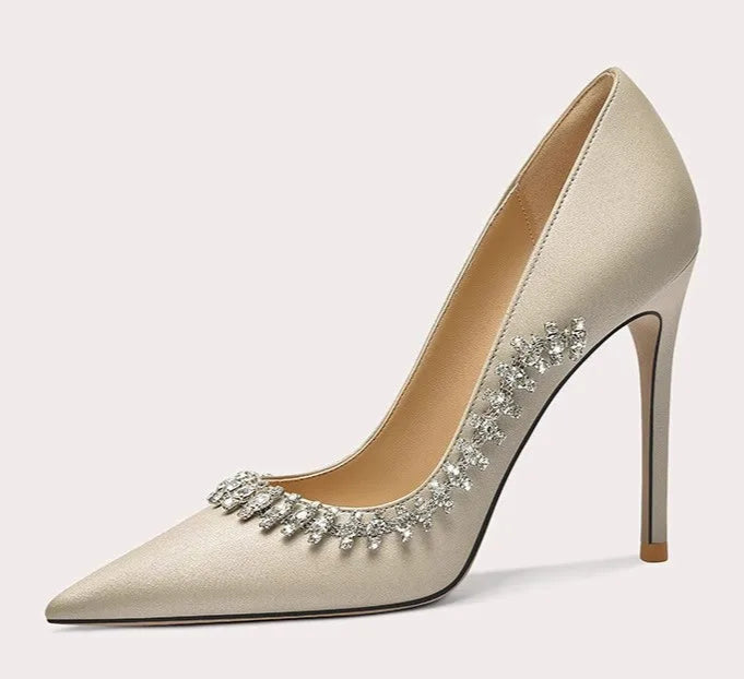 Beige high-heeled shoe with decorative elements on a light gray background