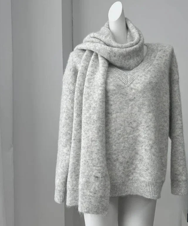 Gray sweater on a mannequin against a gray background with a framed quote.