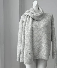 Gray sweater on a mannequin against a gray background with a framed quote.