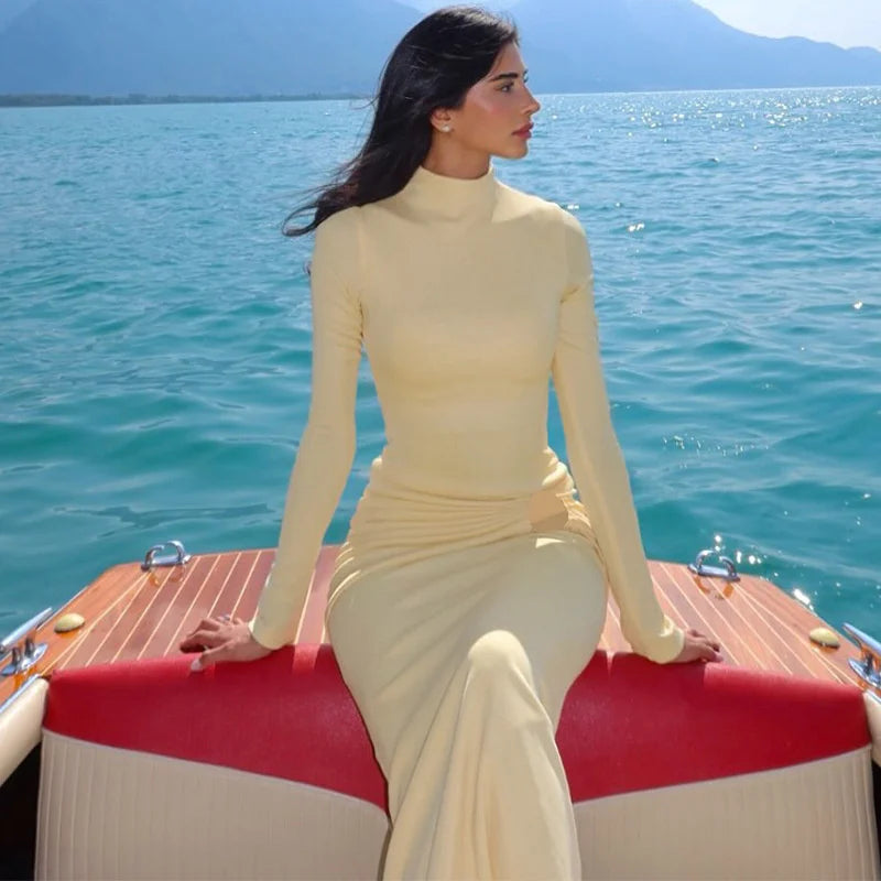 Woman in a beige dress sitting on a boat with a scenic water background