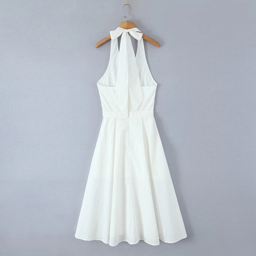 White halter neck dress on a wooden hanger against a gray background