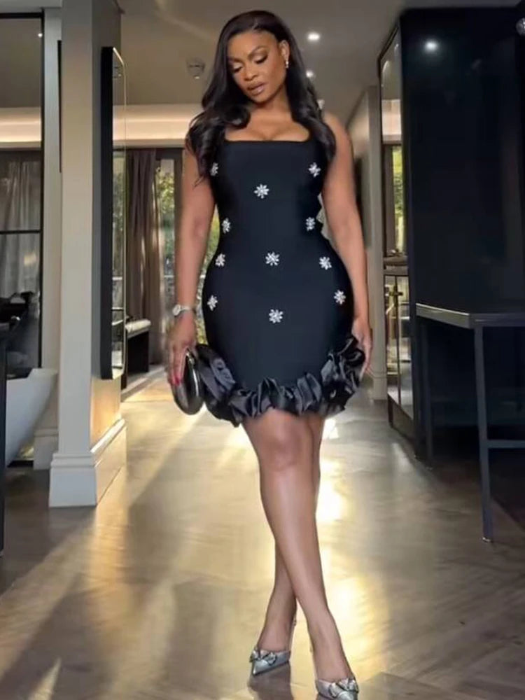 Woman in a black dress with white floral patterns walking in an indoor setting.