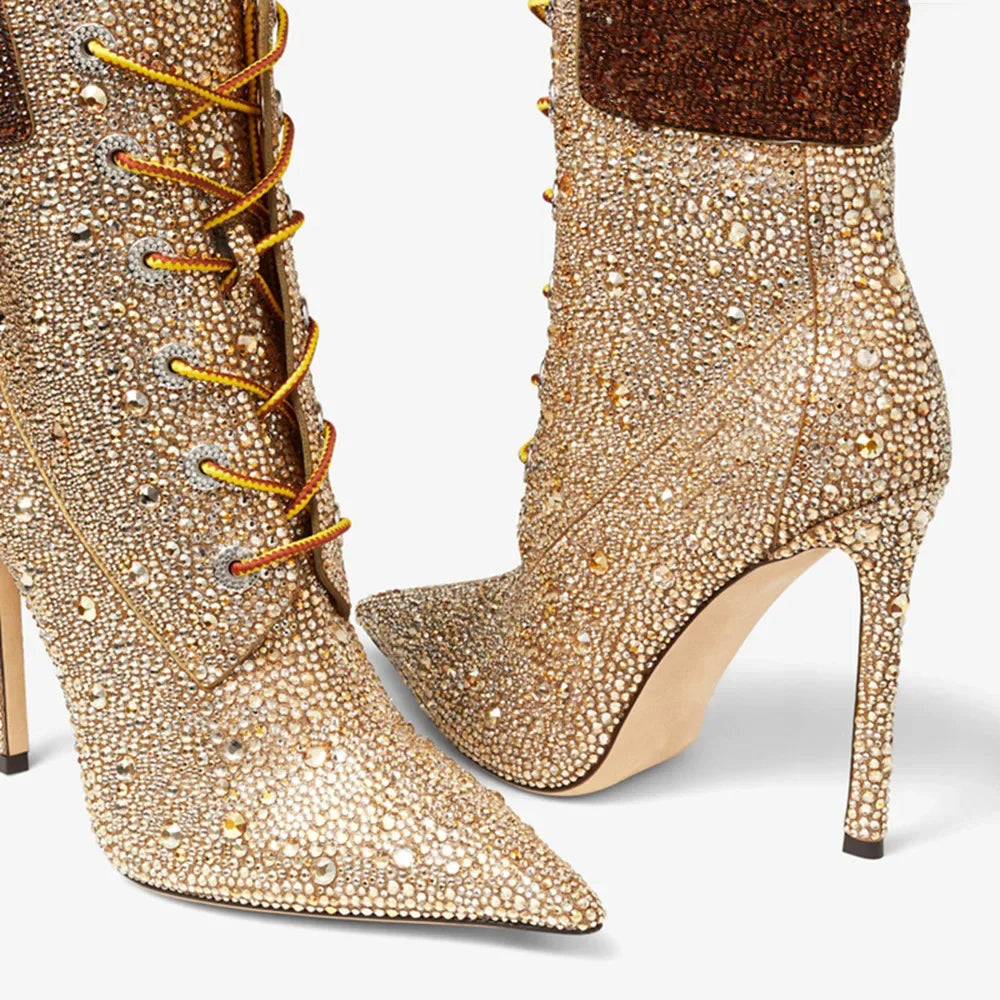 Gold embellished high-heeled boots with orange laces on a white background