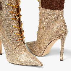 Gold embellished high-heeled boots with orange laces on a white background