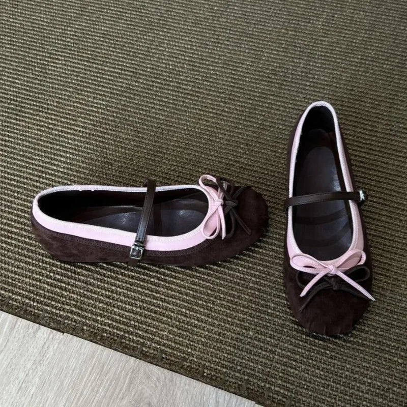 Pair of brown shoes with pink bows on a textured surface