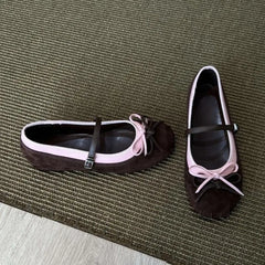 Pair of brown shoes with pink bows on a textured surface