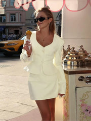 Woman in a light-colored suit holding an ice cream cone on a city street.