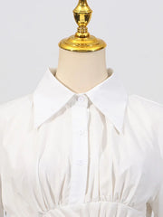 White blouse on a mannequin with a gold top against a white background