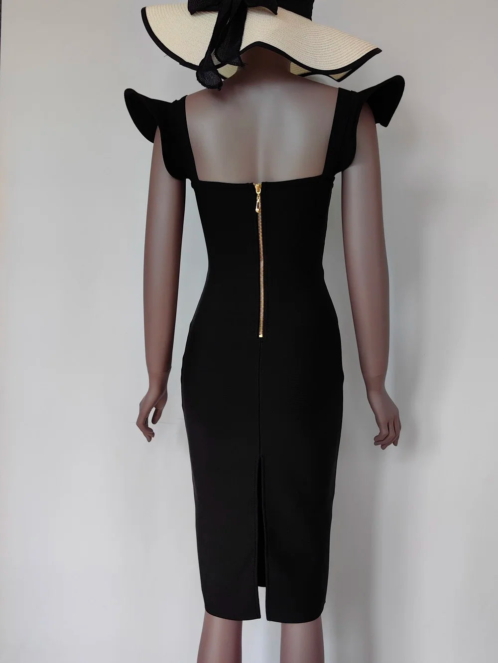 Black dress with ruffled shoulders on a mannequin against a plain background