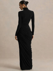 Woman wearing a black long-sleeve gown against a beige background