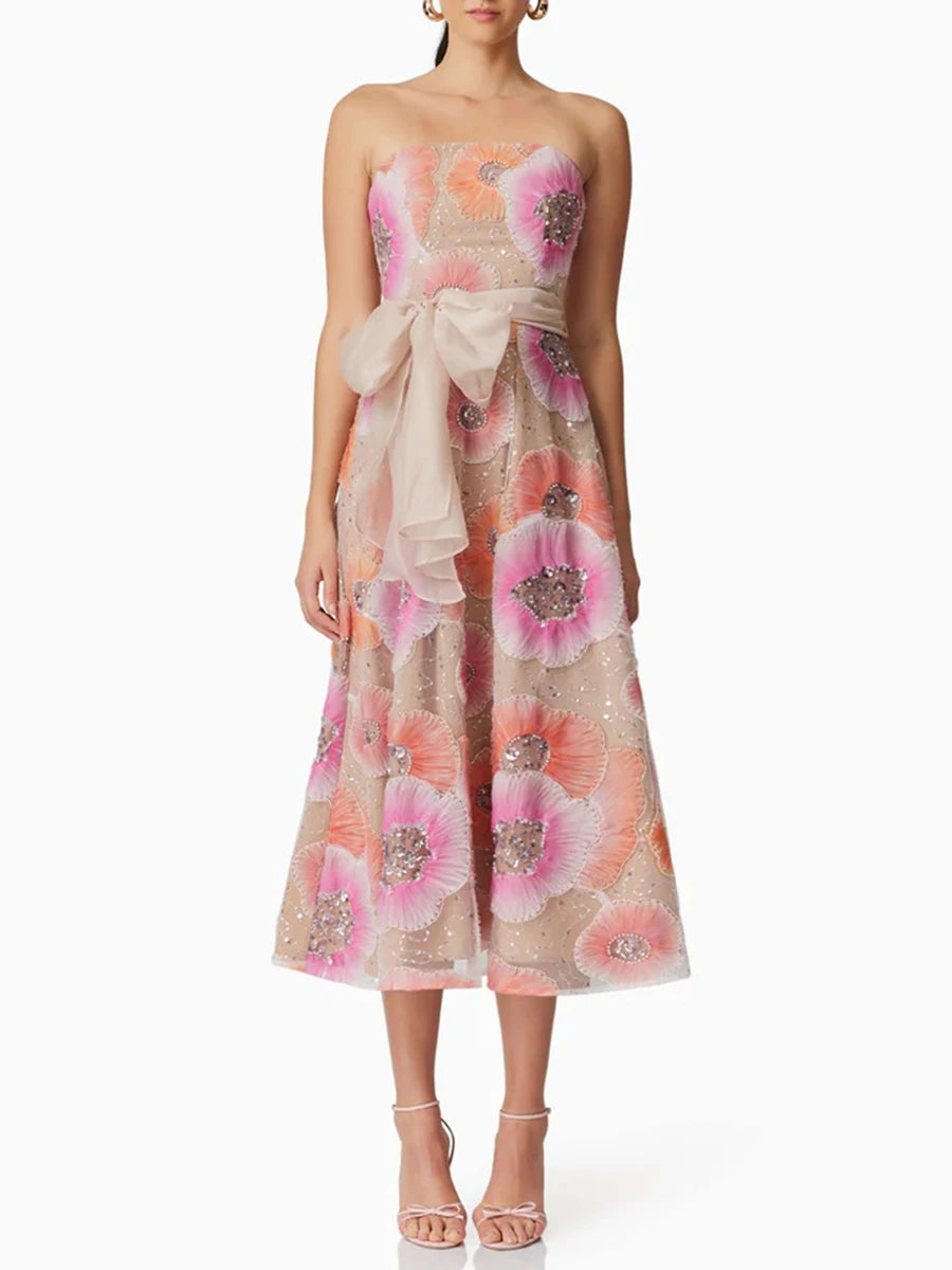 Woman wearing a floral strapless dress with a bow on a white background