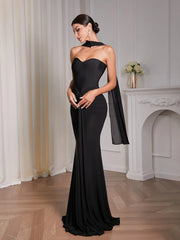 Woman wearing a black evening gown with a cape in an elegant room.