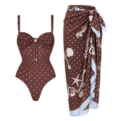 One-piece polka dot swimwear with adjustable straps and tie detail, paired with a coordinating polka dot skirt with seashell print.