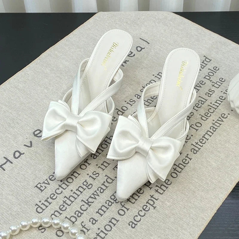 White shoes with bow details on a textured surface