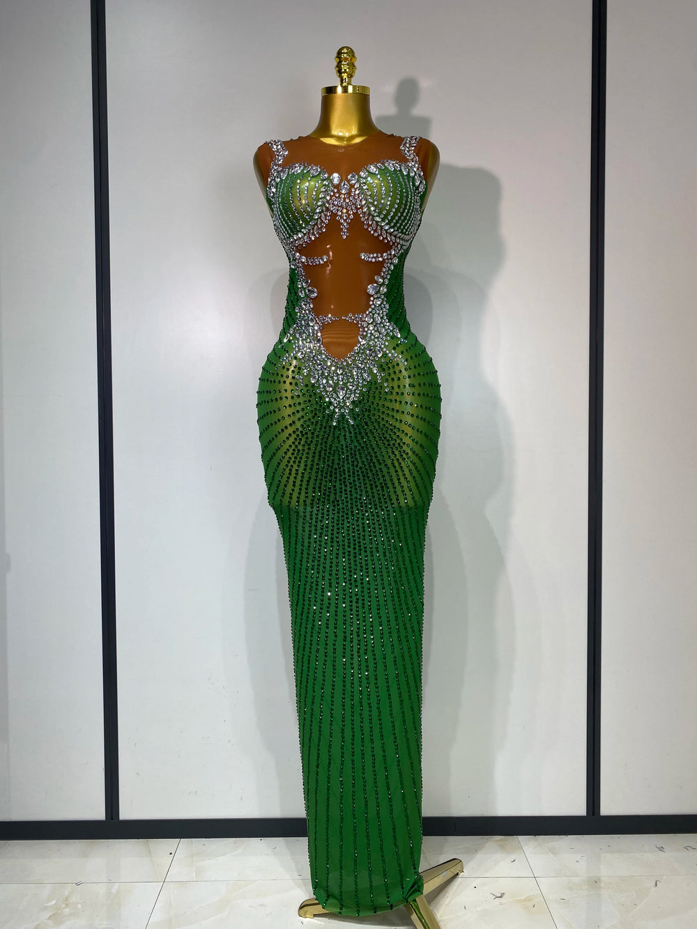 Green evening gown with intricate detailing on a mannequin against a plain background