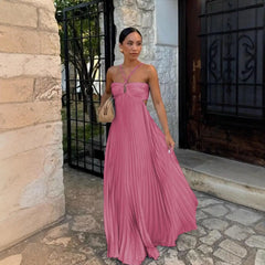 Woman in a pink dress standing in front of a stone wall and metal gate.