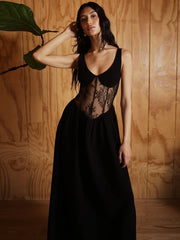 Woman wearing a black lace dress against a wooden wall.