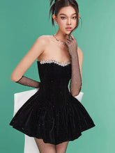 Woman wearing a black strapless dress with white embellishments on a green background