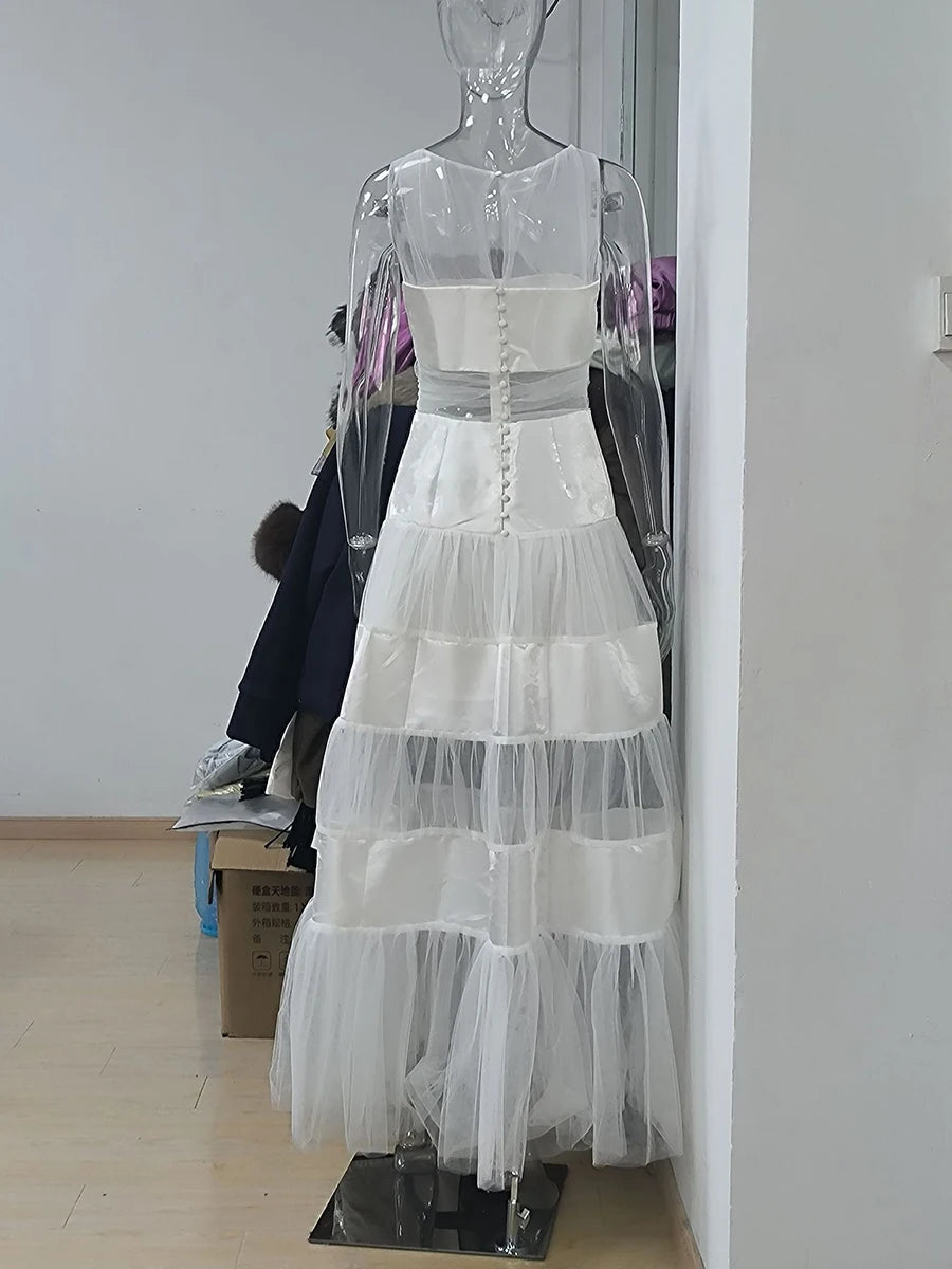 Back view of a white maxi dress with mesh and satin panels on a mannequin