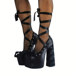 Black platform high-heeled shoes with straps worn with fishnet stockings on a white background