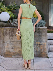Woman wearing a green lace outfit standing outdoors with plants and a light fixture in the background.