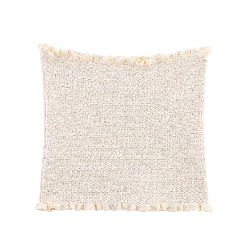 Textured cream pillow with tassel trim on a white background