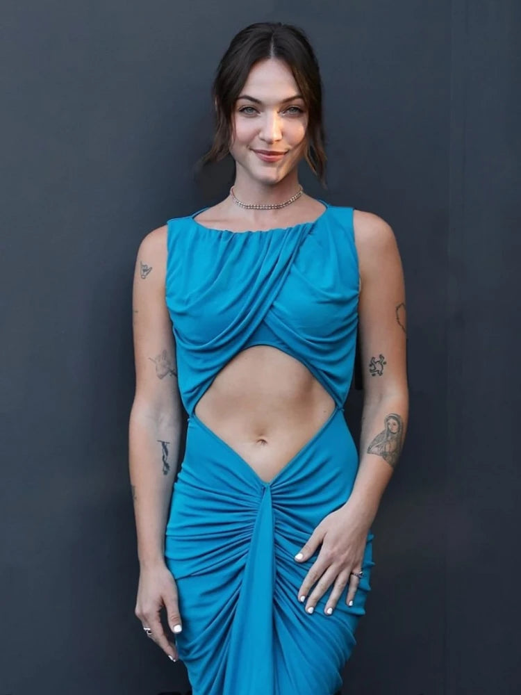 Woman wearing a blue dress with cut-out design against a dark background