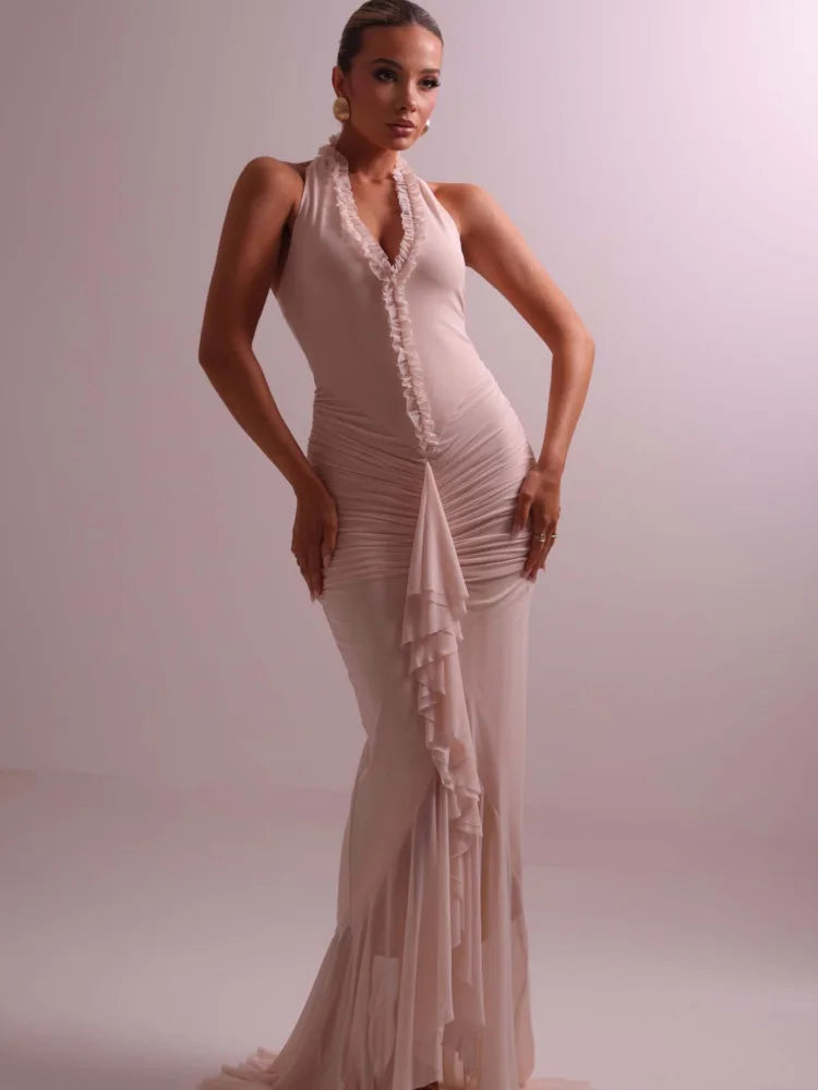 Woman wearing a beige evening gown against a plain background