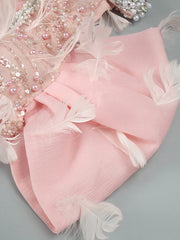 Pink fabric with floral embroidery and beads on a gray background