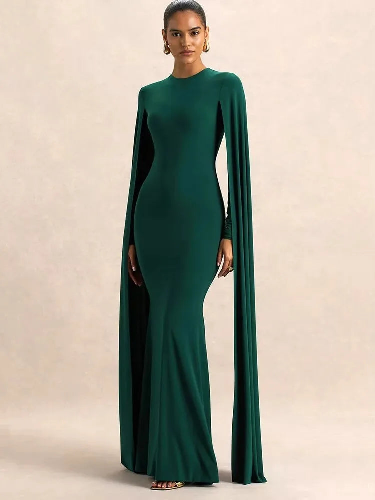 Woman wearing a green evening gown with a cape on a beige background