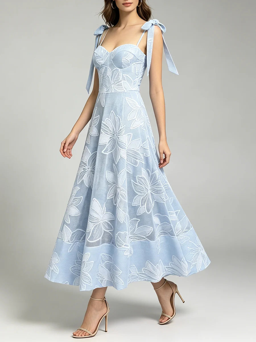 Woman walking in a light blue floral lace midi dress with tie shoulder straps