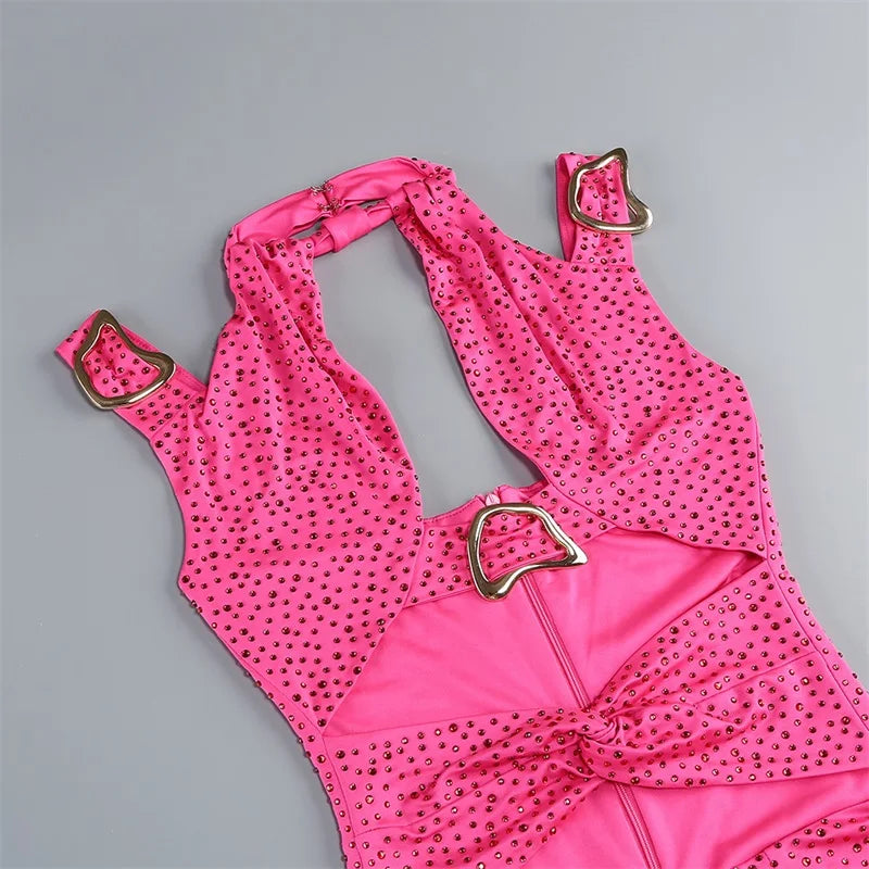 Pink polka dot swimsuit with gold accents on a gray background