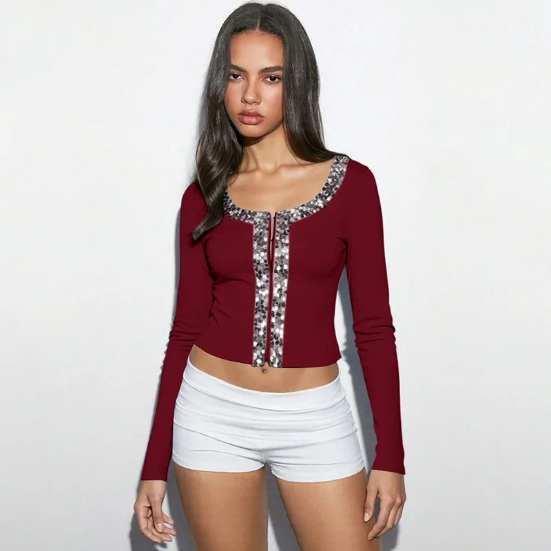 Woman wearing a red long-sleeve top with sequin details and white shorts on a white background