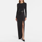 Front view of a woman wearing a black beaded polka dot maxi dress with a high slit.