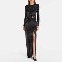 Front view of a woman wearing a black beaded polka dot maxi dress with a high slit.
