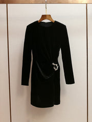 Black dress with a silver belt on a hanger against a neutral background