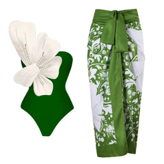 Green one-piece swimsuit with white floral embellishment and pearl details, paired with a green and white floral wrap skirt.