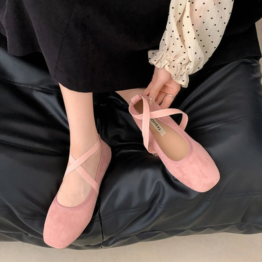 Feet wearing pink square toe ballet flats with criss-cross straps