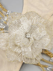 Close-up of a beaded flower accessory with gold and clear beads on a neutral background