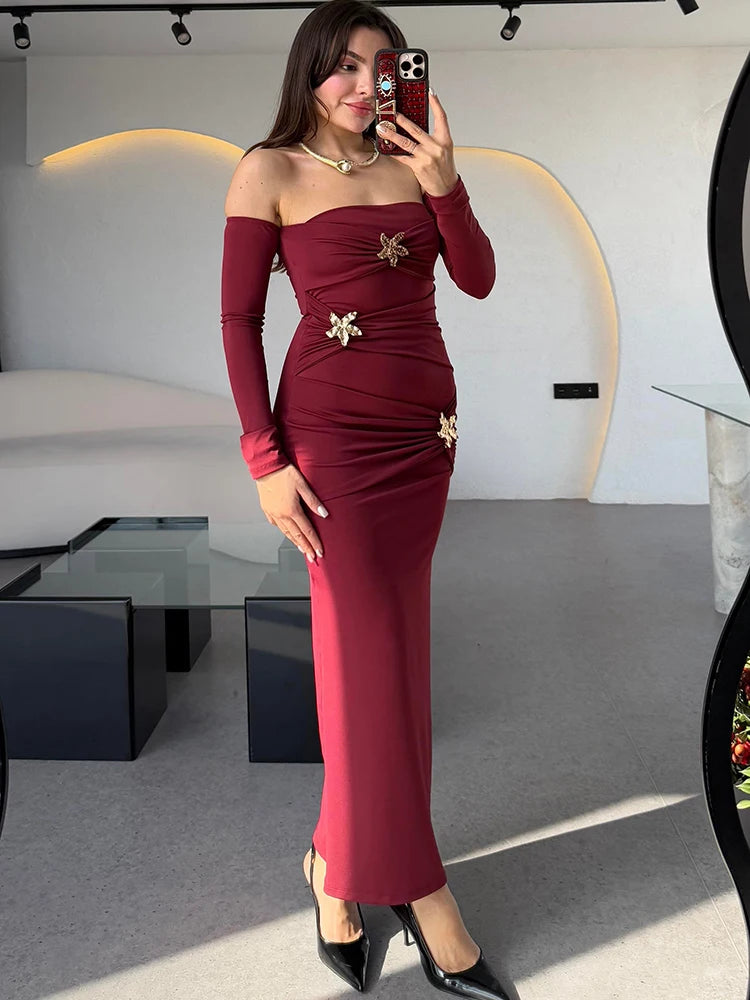 Woman in a burgundy off-shoulder dress with gold accents taking a mirror selfie.