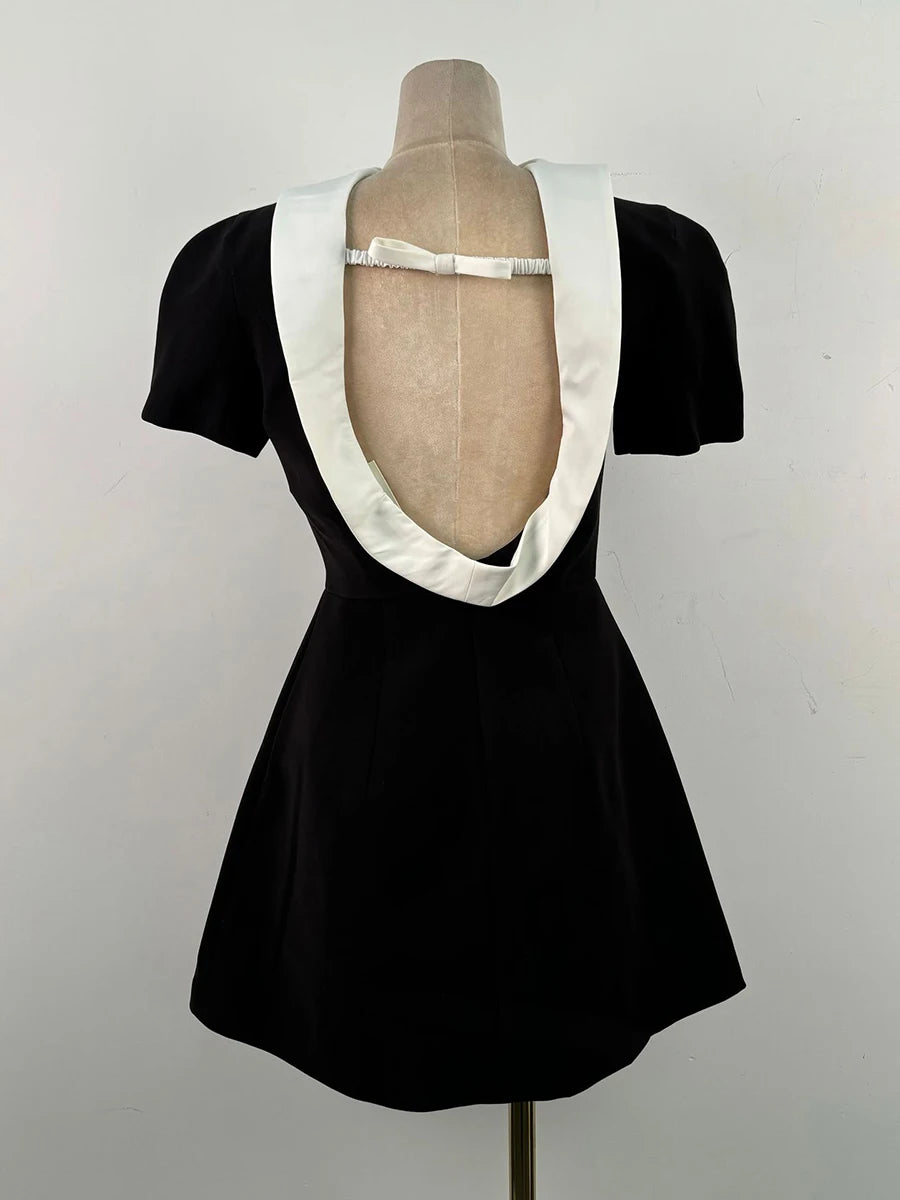 Black dress with white collar on a mannequin against a plain background