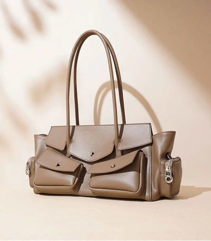 Gray handbag with multiple pockets and handles on a beige background