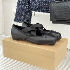 Black ballet flats on a beige box with a blurred background