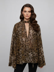 Woman wearing a leopard print blouse against a plain background