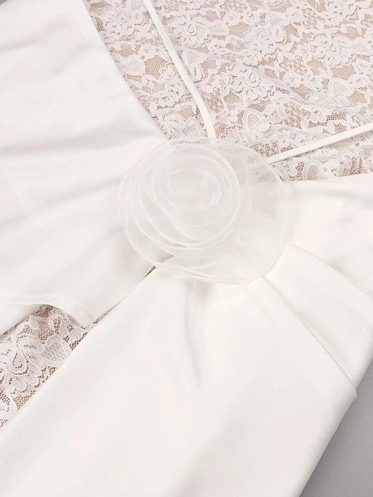 White fabric with lace detailing and a floral bow on a neutral background