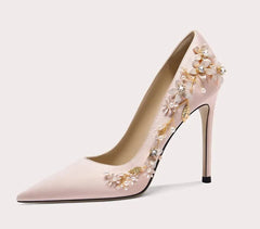 Pink high-heeled shoe with floral embellishments on a light gray background